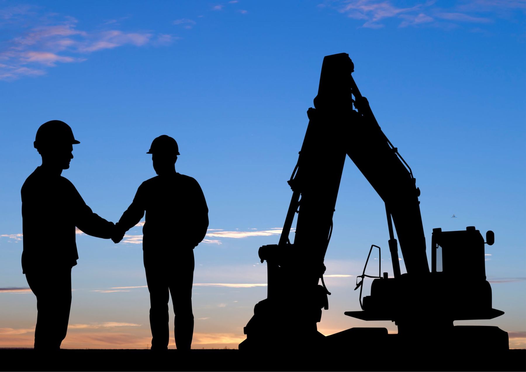 Two workers in hard hats shaking hands at sunset beside an excavator