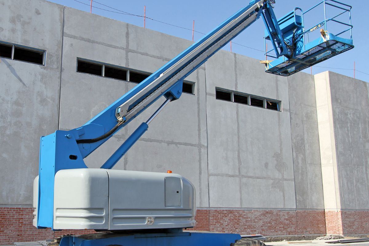 Blue telescopic boom lift positioned against a commercial building under construction